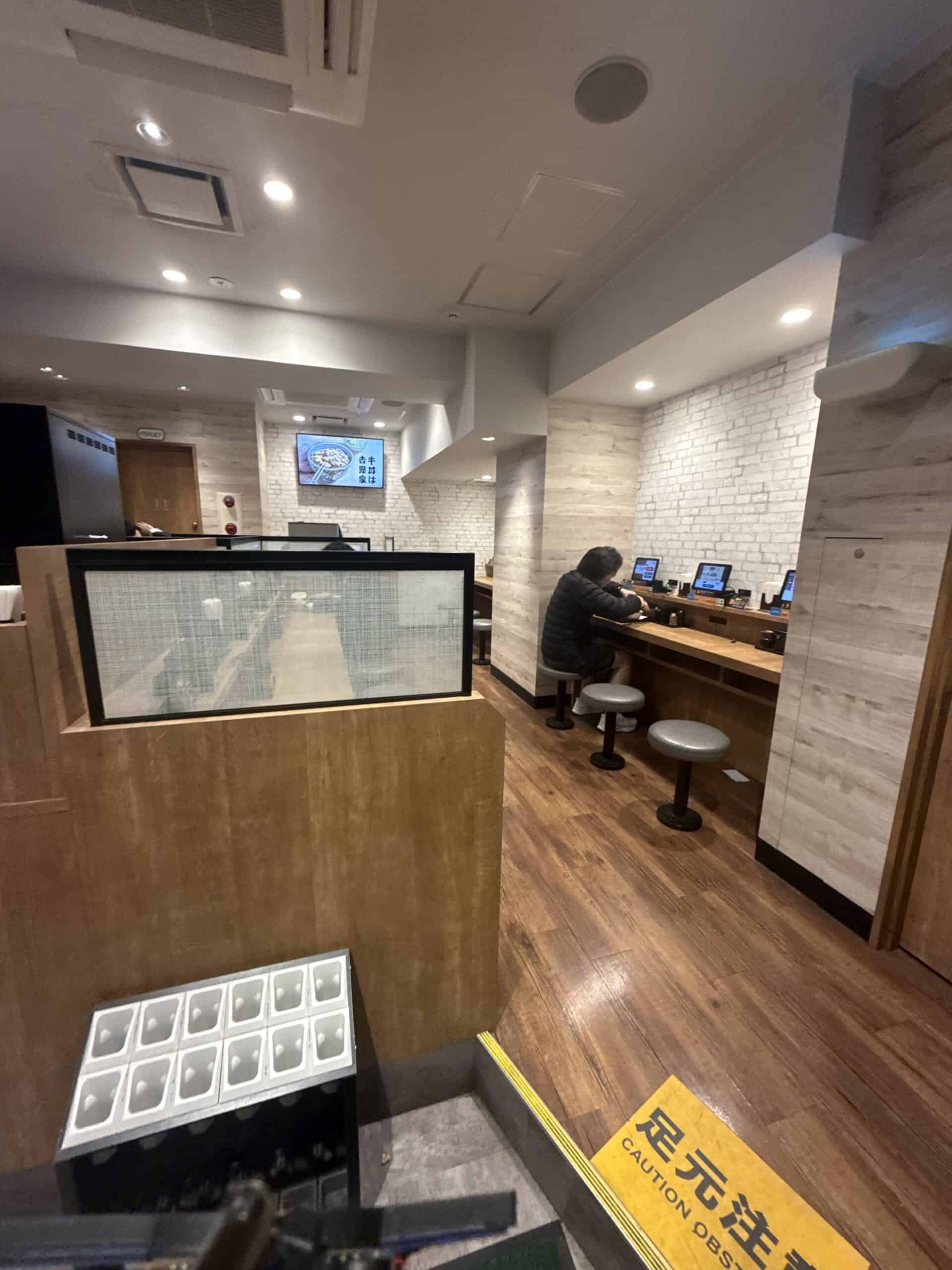 Inside a Yoshinoya restaurant showing counter seats and ordering tablets
